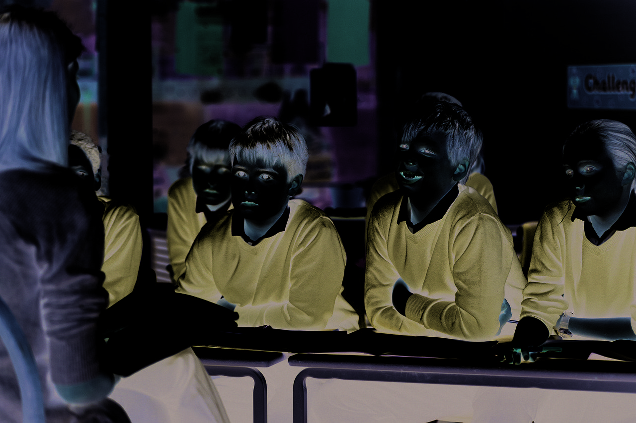 Sala de aula com professora e alunos estudando para uma campanha educacional.